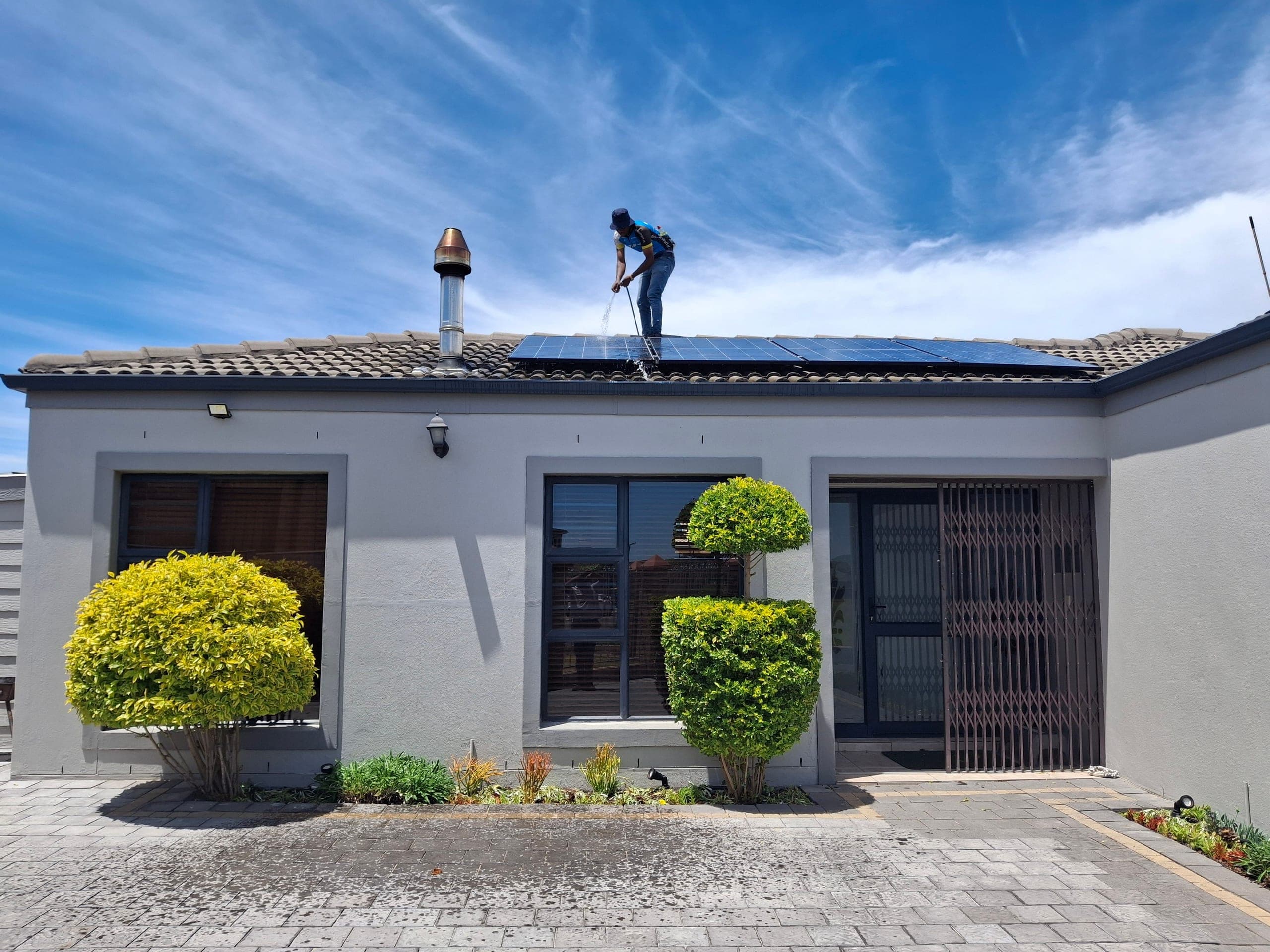 Technicien ENERCOS nettoyant des panneaux solaires sur la toiture d'une maison